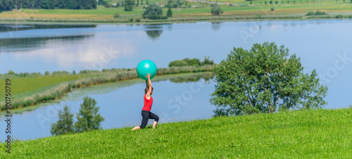 Junge Frau bei Pilates-Übungen mit dem Gymnastikball in der Natur