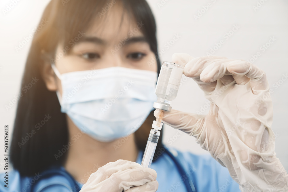 Extracting vaccine fluid liquid from bottle using needle injection for vaccinating patient protection from covid19 coronavirus, asian chinese female doctor nurse medical healthcare worker staff Extracting vaccine fluid liquid from bottle using needle injection for vaccinating patient protection from covid19 coronavirus, asian chinese female doctor nurse medical healthcare worker staff