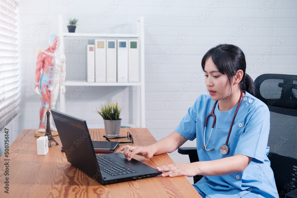 Asian Chinese female doctor using computer laptop in office, professional specialist medical healthcare staff in hospital, wearing white coat stethoscope working during covid19 pandemic. Asian Chinese female doctor using computer laptop in office, professional specialist medical healthcare staff in hospital, wearing white coat stethoscope working during covid19 pandemic.