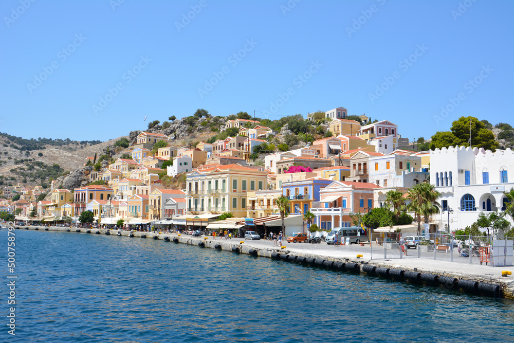 waterfront of greek island Symi with coloured buildings and hills on background