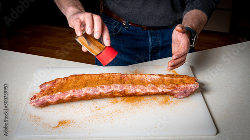 фотографія Man sprinkles a seasoning mixture on ribs before smoking