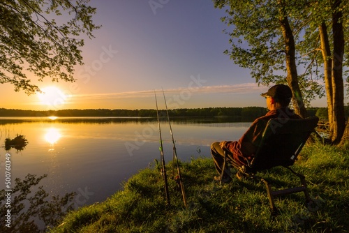 Angler sitting on fishing chair during sunrise photo