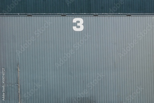 Gray corrugated metal door with the number three in white