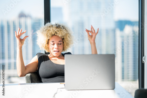 Young Light Skinned African-American Woman with Blonde Afro Having a Zen Moment in Front of Her Laptop