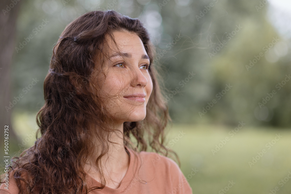 a woman with curly hair meditates in the park. yoga and meditation for mental and physical health. a beautiful young woman calmly looks thoughtfully and engages in breathing and spiritual practices