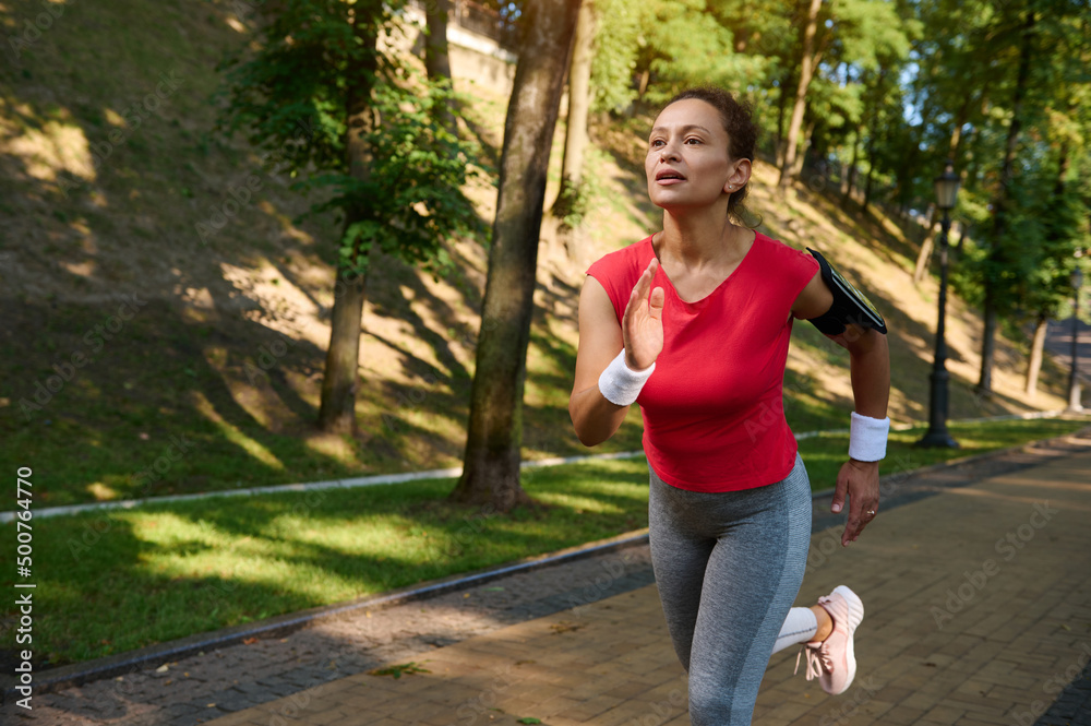 Female runner enjoying morning jog in the city park on a beautiful summer day Female runner enjoying morning jog in the city park on a beautiful summer day