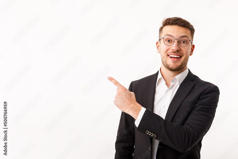 A young businessman in a business suit points to copyspace. A young businessman in a business suit points to copyspace.