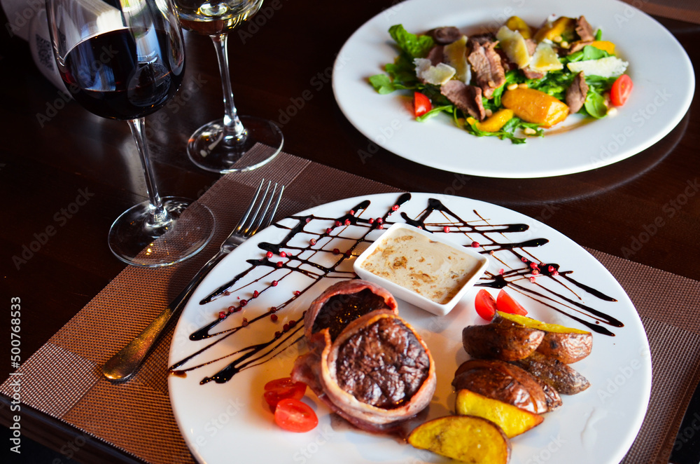 Salad, meat and wine in a restaurant, romantic dinner for two