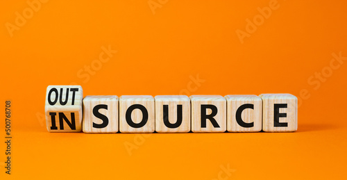 Outsource or insource symbol. Turned a wooden cube and changed the concept word Outsource to Insource. Beautiful orange table orange background, copy space. Business outsource or insource concept.