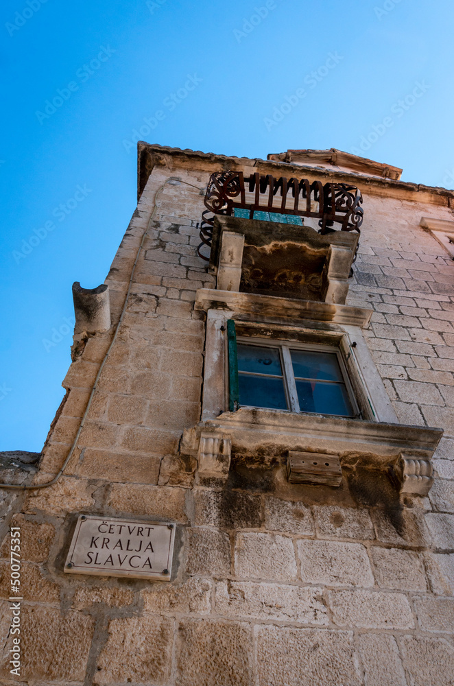 View looking up at an  ancient building and street name sign, in the old town of Omis, Croatia