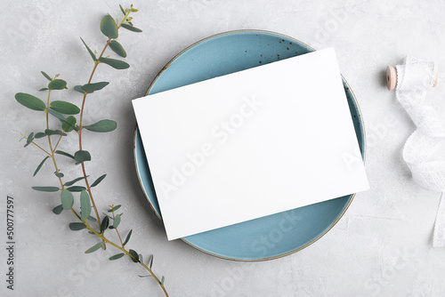 Wedding stationery invitation card mockup 7x5 on grey background with eucalyptus, Menu card mockup with festive wedding or birthday table setting, blue ceramic plate. Minimal blank card mockup photo