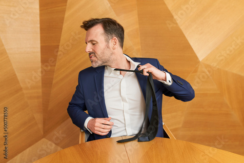 Businessman leaving corporate work taking off his tie with anger