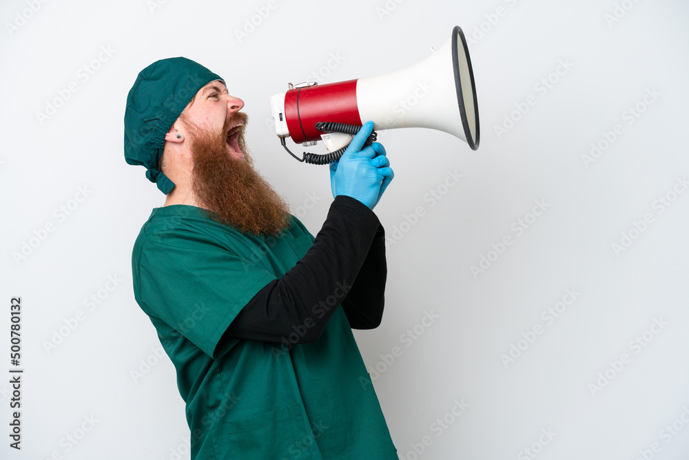 Surgeon redhead man in green uniform isolated on white background shouting through a megaphone