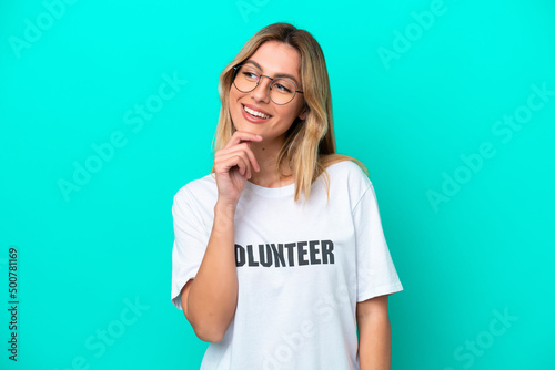 Young volunteer Uruguayan woman isolated on blue background looking to the side and smiling
