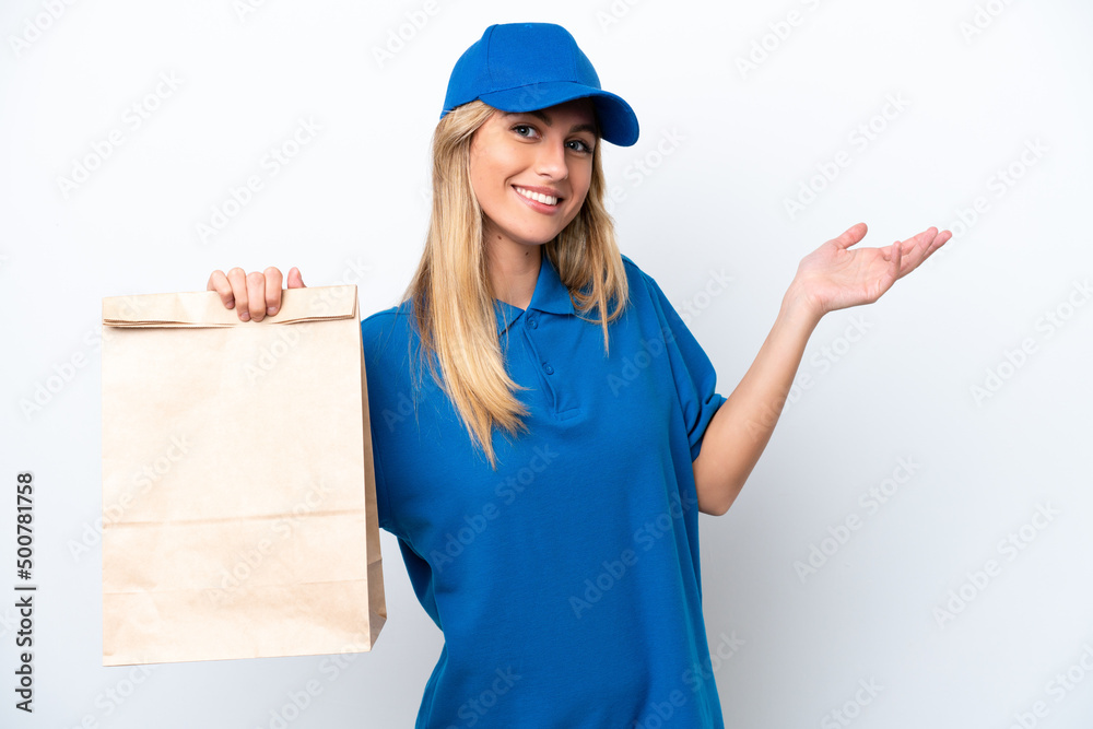 Young Uruguayan woman taking a bag of takeaway food isolated on white background extending hands to the side for inviting to come Young Uruguayan woman taking a bag of takeaway food isolated on white background extending hands to the side for inviting to come