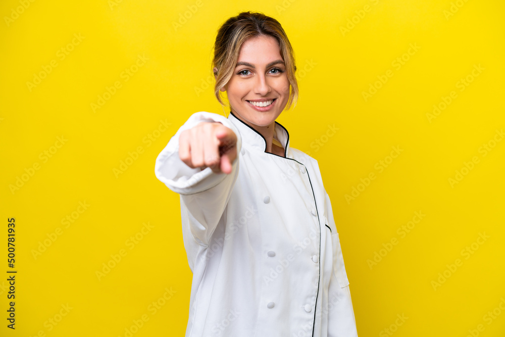 Uruguayan chef woman isolated on yellow background points finger at you with a confident expression Uruguayan chef woman isolated on yellow background points finger at you with a confident expression