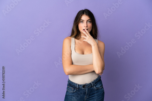 Young caucasian woman isolated on purple background surprised and shocked while looking right