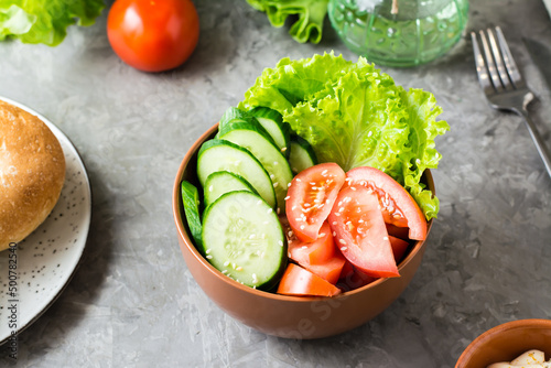 Fresh vegetable bowl with cucumber, tomato and lettuce on the table at home. Close-up
