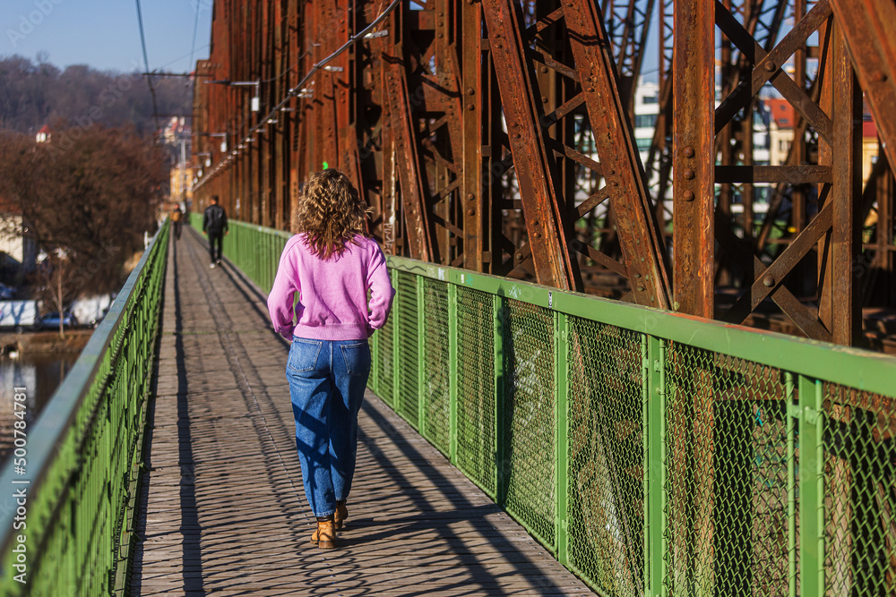 a young woman in blue jeans walks down the footbridge next to the railway line a young woman in blue jeans walks down the footbridge next to the railway line