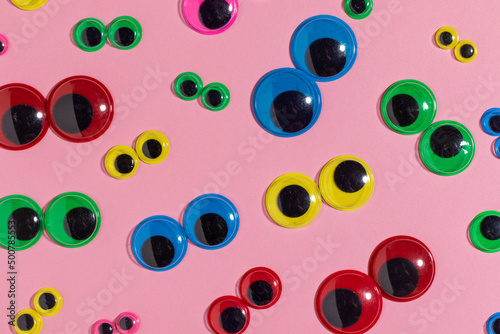 Multicolored plastic eyes on a pink background. Googly eyes. photo