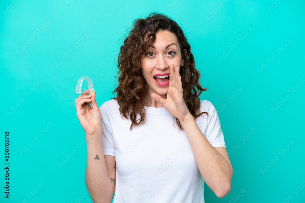 Young caucasian woman holding a envisaging isolated on blue background shouting with mouth wide open Young caucasian woman holding a envisaging isolated on blue background shouting with mouth wide open