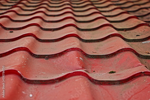 Old dirty tiles on the roof of the building. The texture of the red background.