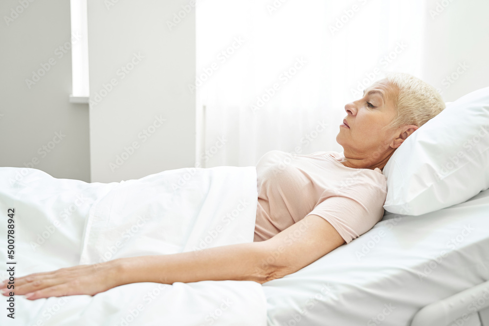 Female pensioner resting in bed ward of medical center Female pensioner resting in bed ward of medical center
