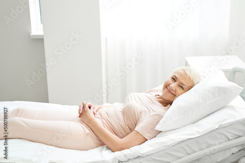 Quadro su tela Elderly person lying in bed in medical center