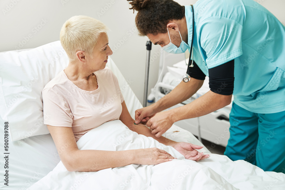 Fototapeta premium Doctor conducting intravenous therapy to elderly citizen