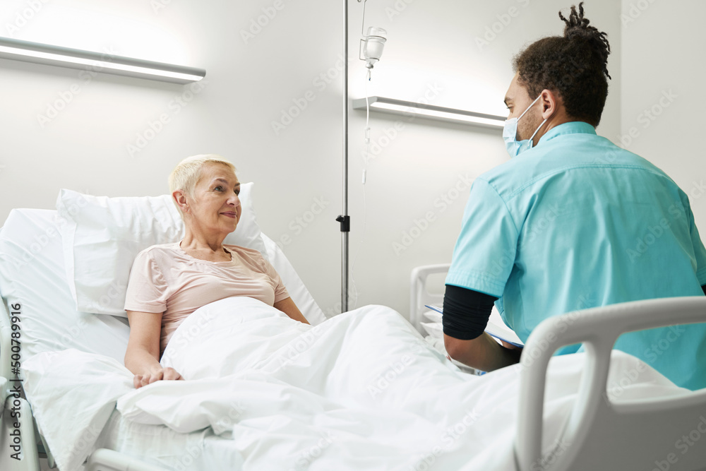 Obraz premium Doctor listening to old woman in hospital bed