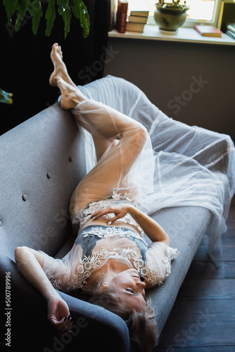 young, pretty, emotional blonde girl lying on the bed, top view, side view, view through the green leaves. Selective focus. Relax and rest