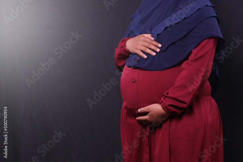 big pregnant asian woman in red dress on dark background in studio © sf_freelancer