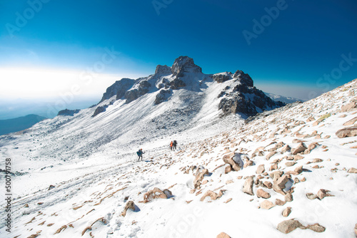 group of mountaineers walking through a landscape full of snow and rocks on a morning in the mountains of Mexico photo