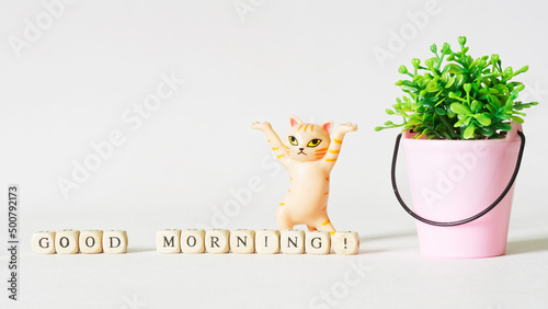 Quadro su tela Funny dancing toy cat next to a bucket with a and the inscription good morning