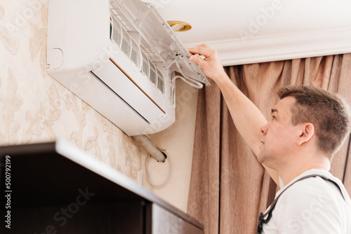 the repairman cleans or repairs the air conditioner in the house. 