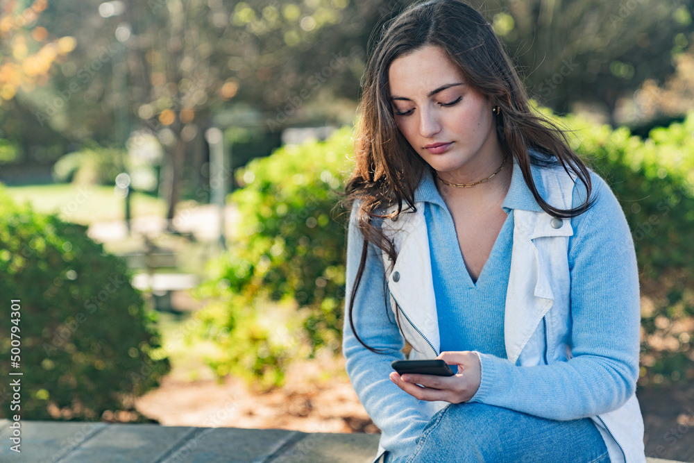 Beautiful girl using her mobile phone in a park Beautiful girl using her mobile phone in a park