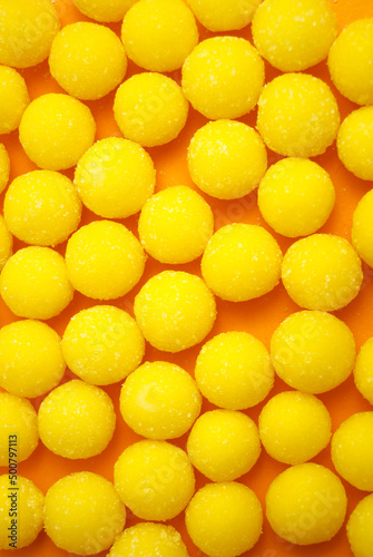 Yellow candy drops in sugar. Background.