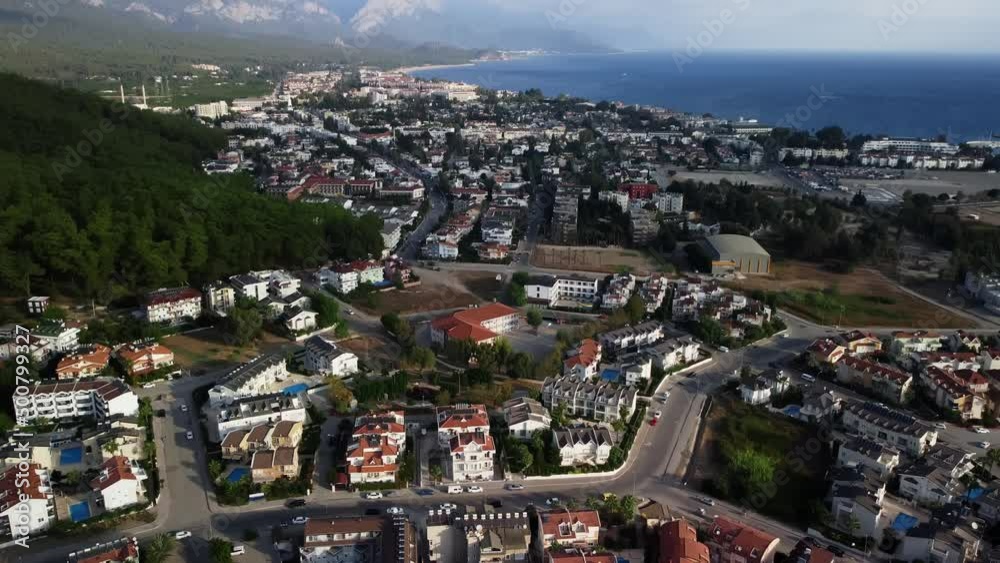 Aerial footage of Kemer in Turkey with hotels and villas located between sea and mountains. Drone point of view of touristic city with residential buildings on the shoreline. Travel destination theme.