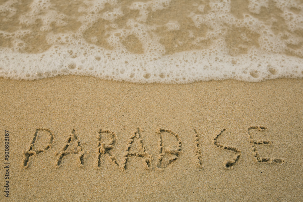 Fototapeta premium Paradise - handwritten on the soft beach sand.