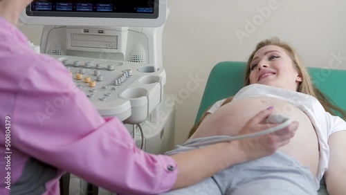 The doctor uses ultrasound equipment when examining a pregnant woman. A professional female obstetrician-gynecologist conducts a prenatal examination of the expectant mother in a hospital