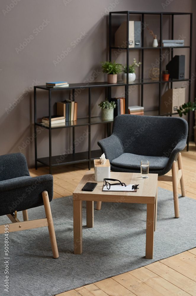Fototapeta premium Vertical no people shot of modern psychologist office interior in gray and brown colors with two chairs and coffee table