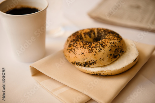 poppyseed bagel with coffee and news paper photo