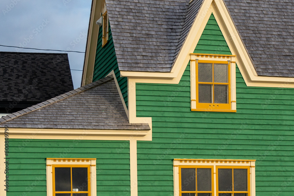 The exterior of a vibrant green color cape cod house with clapboard horizontal wooden board