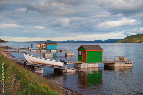 Burlington, Newfoundland, Canada-May 2022: A small fishing community, with small white fishing boats on a wooden slipway in the harbour with vintage colorful wooden buildings along the shoreline.  photo