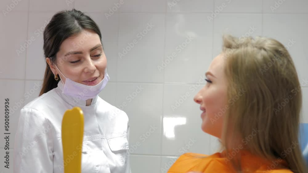A charming pregnant girl in the dentist's chair, smiling and looking in the mirror, showing a snow-white smile after the teeth whitening procedure.Dental clinic.Doctor's consultation. Dental treatment