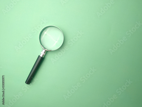 Magnifying glass on a green background with copy and text space.