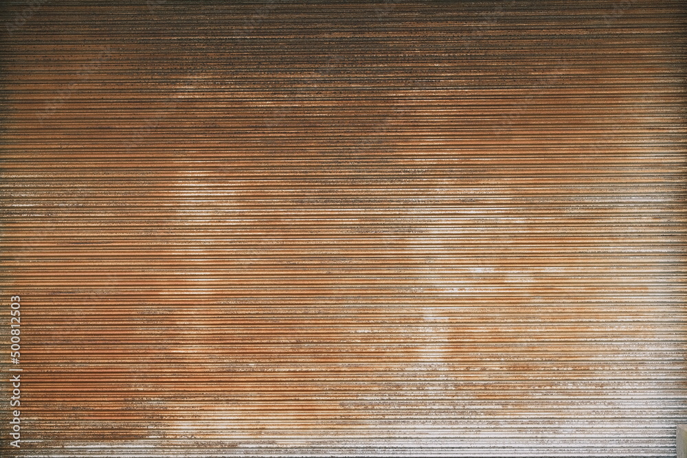 very large metal roller door of a warehouse with some rust and aged colours in the industrial area very large metal roller door of a warehouse with some rust and aged colours in the industrial area