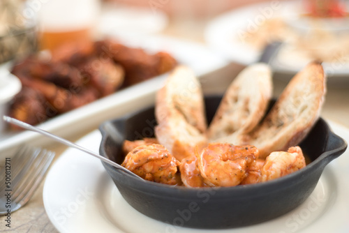 Barbecue shrimp with bread in a small cast iron skillet.