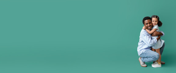 Portrait of little African-American girl hugging her father on green background with space for text