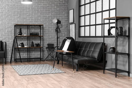 Interior of modern photo studio with shelving units  couch and professional equipment